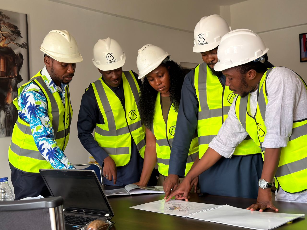 Services Group of engineers in safety gear reviewing blueprints indoors.